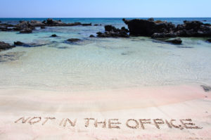 Beach scene with out of office written in the sand. Image courtesy of DepositPhotos.